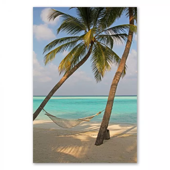 Weisse Hängematte zwischen zwei Palmen an einem paradiesischen Strand mit türkisfarbenem Wasser.